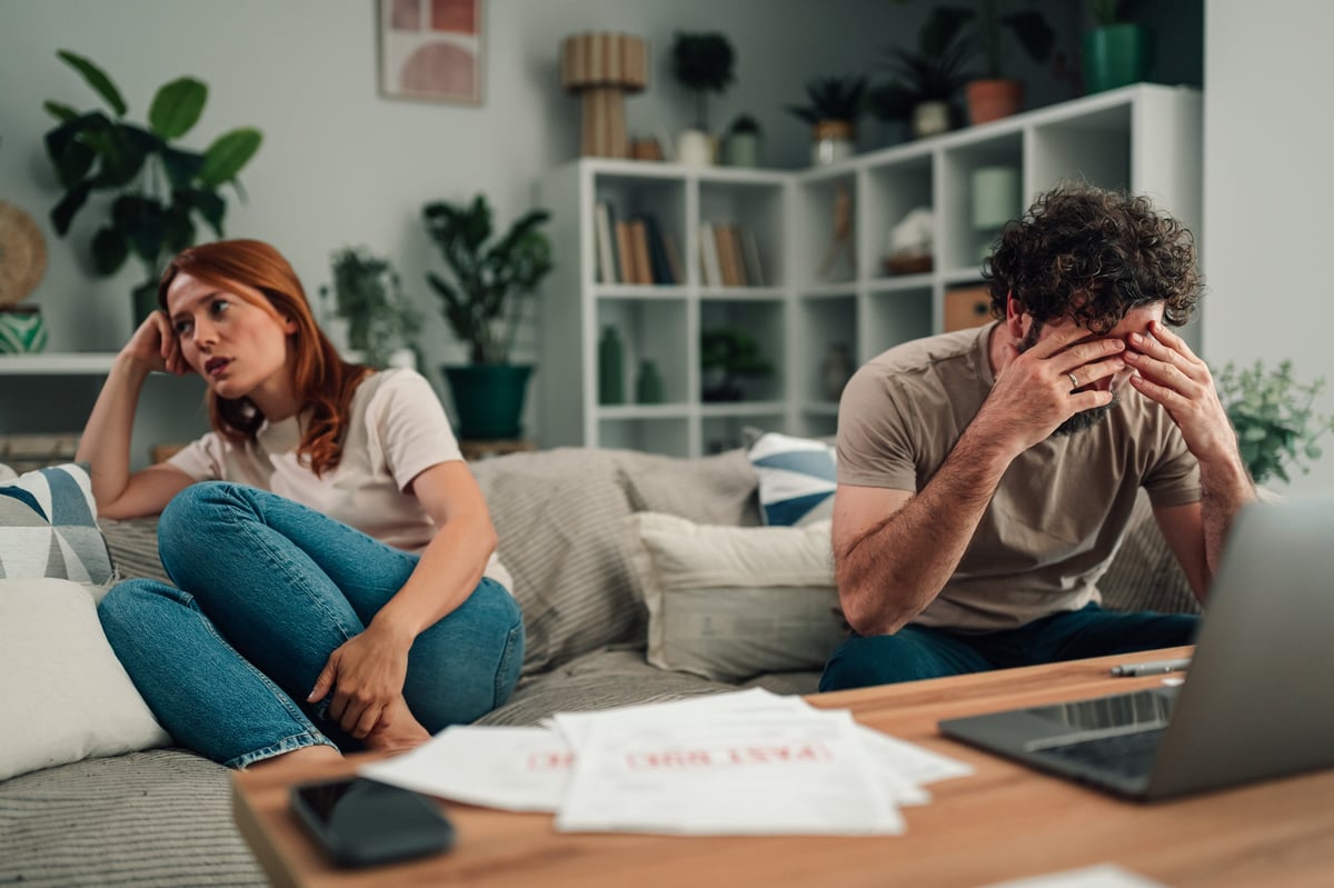 Couple experiencing financial stress and relationship conflict at home, dealing with past due bills and debt